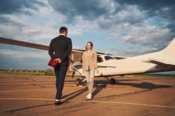 Beautiful couple in love standing near plane at airfield