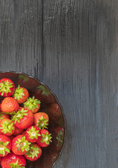 Top view of a juicy garden strawberry, which lies in a glass plate in the lower left corner