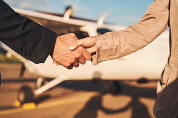 Business colleagues shaking hands outdoors at airdrome