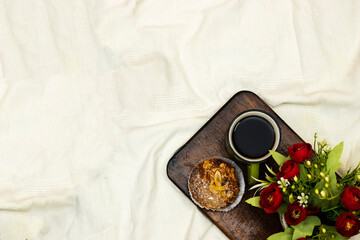 cup of hot coffee with almonds pie, flowers pot on white bed background, vintage tone, top view. Lifestyle concept