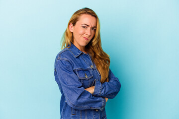 Caucasian woman isolated on blue background frowning face in displeasure, keeps arms folded.