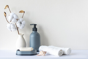 Fototapeta na wymiar Bathroom interior in beige pastel tone. White shelf in bathroom with towels, soap, shampoo bottle, houseplant. Mockup with space for text. Minimal composition.