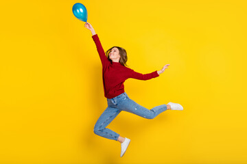 Full body profile photo of cool millennial lady jump with balloon wear sweater jeans isolated on vivid yellow color background