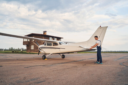 Male worker inspecting aircraft outdoors at aerodrome