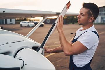 Male worker inspecting aircraft propeller at aerodrome - obrazy, fototapety, plakaty