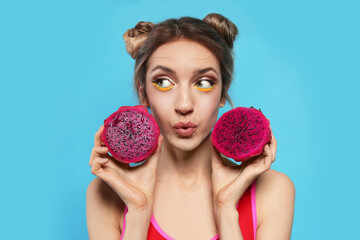 Young woman with fresh pitahaya on light blue background. Exotic fruit