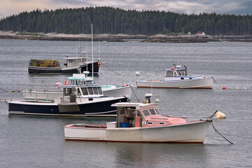 Peaceful summer afternoon scene in coastal Maine. Colorful lobster boats anchored in picturesque...
