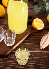 Italian drink lemon liqueur limoncello in a bottle and empty glasses on the wooden table