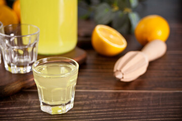 Italian drink lemon liqueur limoncello in a bottle and empty glasses on the wooden table