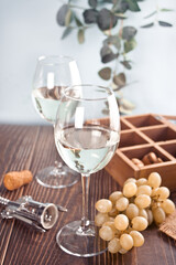 Glasses of white grape wine with grapes and wooden box on the background