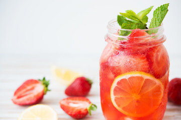 Fototapeta na wymiar Cold summer strawberry lemonade in a jar on a white background, selective focus