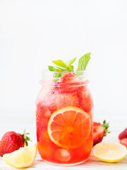 Cold summer strawberry lemonade in a jar on a white background, selective focus