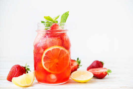 Cold summer strawberry lemonade in a jar on a white background, selective focus