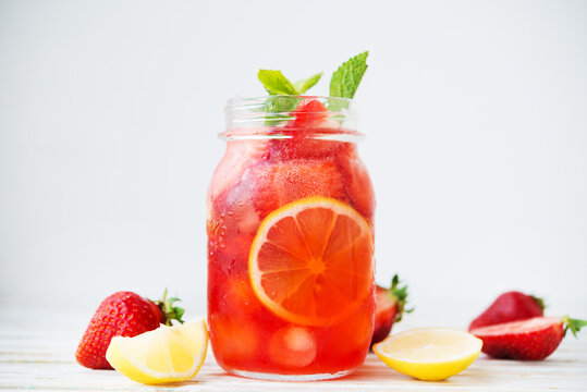 Cold summer strawberry lemonade in a jar on a white background