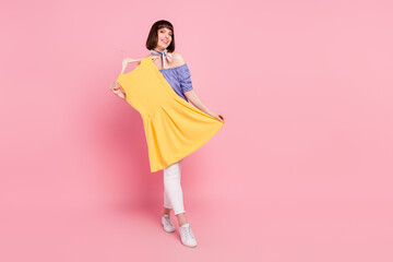 Full length body size photo woman fitting clothes dreamy smiling happy isolated on pastel pink...