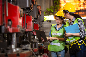 Two female engineers or technician worker wearing safety hard helmet discuss project in industry...