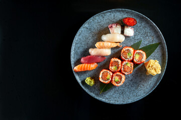 An appetizing sushi set consisting of various nigiri and uramaki with salmon, avocado and tobiko caviar. Japanese traditional cuisine. Food delivery. Isolated on black