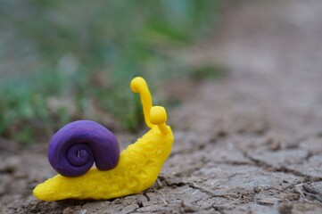 A snail figurine made of plasticine in the green grass. A symbol of spring.