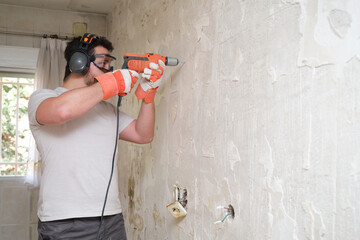Builder drilling holes in a wall with an electric drill at the construction site. Construction...