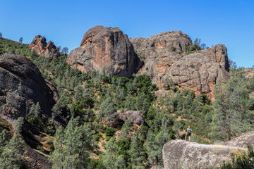 Woman standing rock overlooking  the landscape of Pinnacles National Park in California