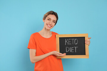 Woman holding blackboard with phrase Keto Diet on light blue background