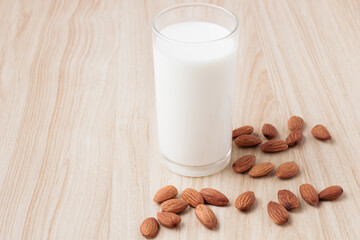 almond milk in glass with nuts around on wood background.selective focus.front view.copy space.