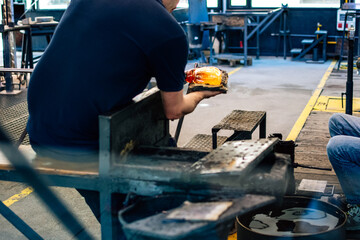 Glass artisan working on a piece of hot glass.