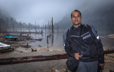 Naklejka premium young man standing at the shore of lake at morning with buddhist flags