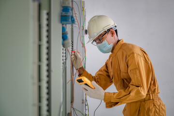 Electrical engineer inspects the electrical system in the factory. Electrician is repairing a...