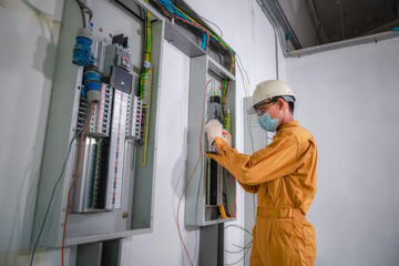 Electrical engineer inspects the electrical system in the factory. Electrician is repairing a...