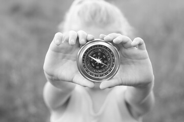 Old classic navigation compass in hands on natural background as symbol of tourism with compass,...