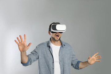 Man using virtual reality headset on grey background