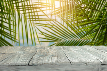 Wooden table on a hot day and exotic palm trees in the background 