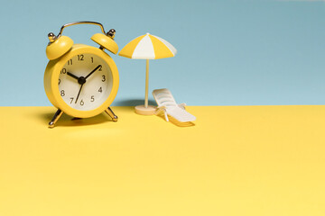 Time to travel. Sun lounger, yellow umbrella and alarm clock.