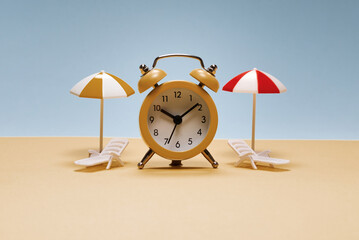 Time to travel. Sun lounger, yellow umbrella and alarm clock.