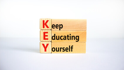 Naklejka premium KEY, keep educating yourself symbol. Wooden blocks with words 'KEY, keep educating yourself'. Beautiful white background, copy space. Business, educational and KEY, keep educating yourself concept.
