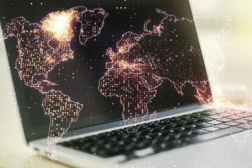 Abstract creative world map on modern laptop background, international trading concept. Multiexposure