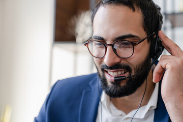 Close up portrait of a confident Arabian young businessman in headset speaking on conference call...