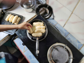 Hand holding bread dip into frying pan background. Stock photo.