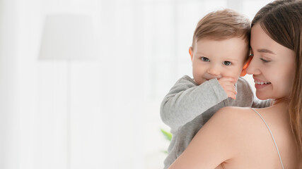 Cropped close up portrait of a small little kid child gnawing fingers because of teething, mother...