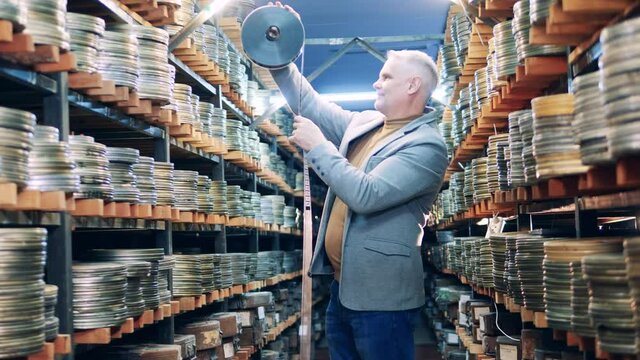 An archivist is inspecting vintage movie tapes