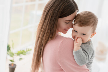 Cheerful caucasian young mother nanny babysitter embracing small little child kid son daughter...