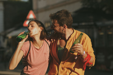 Fototapeta na wymiar Young couple dancing on the street and opening beer