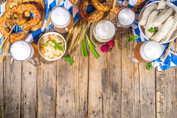 Fototapeta na wymiar Oktoberfest food background, Traditional bavarian holiday food menu, sausages with pretzels, sauerkraut, beer glass and mugs on wooden sun lighted background copy space top view copy space