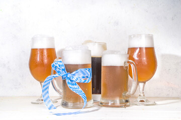 Oktoberfest various beer glasses and mugs with pretzel, wheat and hops. Bar and pub menu, invitation card background on wooden background copy space