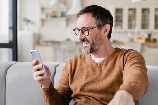 Caucasian middle-aged man using smart phone for web browsing, social media, checking e-mails, e-banking, booking tickets online on quarantine. Wireless technology concept