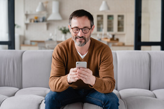 Front view caucasian middle-aged man using smart phone for web browsing, social media, checking e-mails, e-banking, booking tickets online on quarantine.