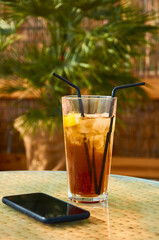 Cold drink cocktail and telefon on the table. Summer rest
