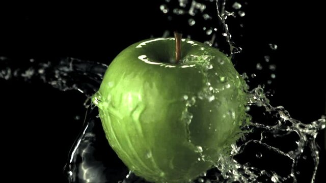 Super slow motion green apple with splashes of water. On a black background.Filmed on a high-speed camera at 1000 fps