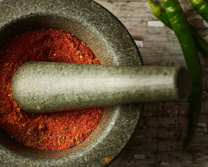 Ground spices in pestle and mortar closeup on natural wooden table macro isolated